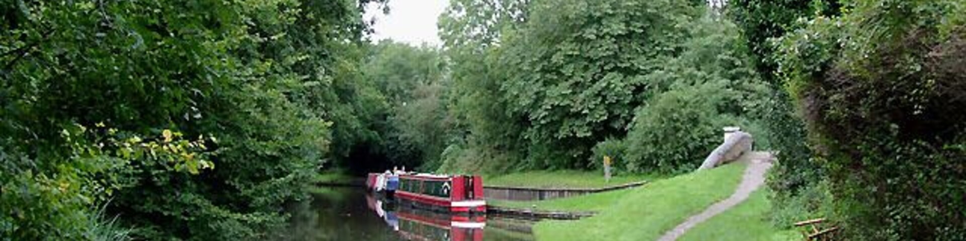 Stratford-upon-Avon Canal at Hockley Heath, Solihull. The canal is seen here from below the arch of Bridge No 25, which carries the A4300 Stratford Road from Solihull. Ahead to the right is a short canal arm which used to lead to a coal wharf. 1716384 The Stratford-upon-Avon Canal was built from King's Norton Junction (with the Worcester and Birmingham Canal) to Kingswood Junction (with the Warwick and Birmingham Canal - now Grand Union Canal) by 1803. A second phase of construction started in 1812, and by 1815 was connected to the River Avon in Stratford. Total length 25.5 miles, with 54 locks.