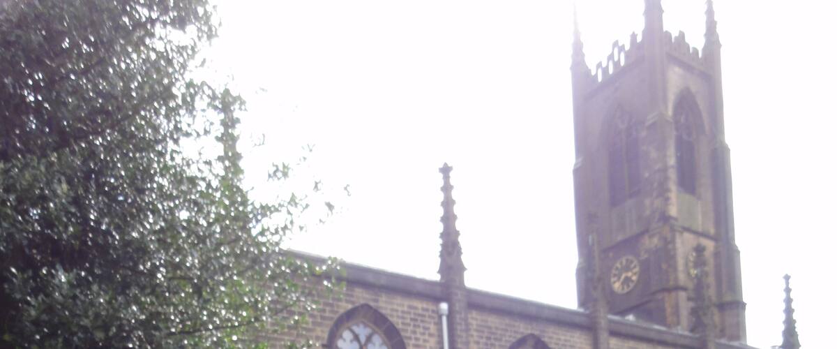 A church with a tall tower and arched windows, surrounded by a cemetery with headstones.