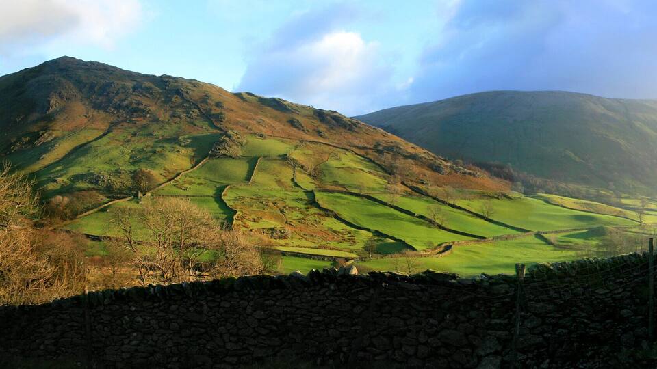 A mountain landscape with a stone wall and a cyclist.