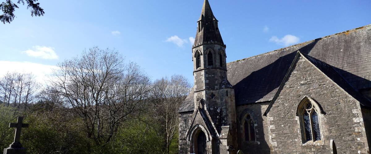 A church with a tall steeple and a cross at the entrance.
