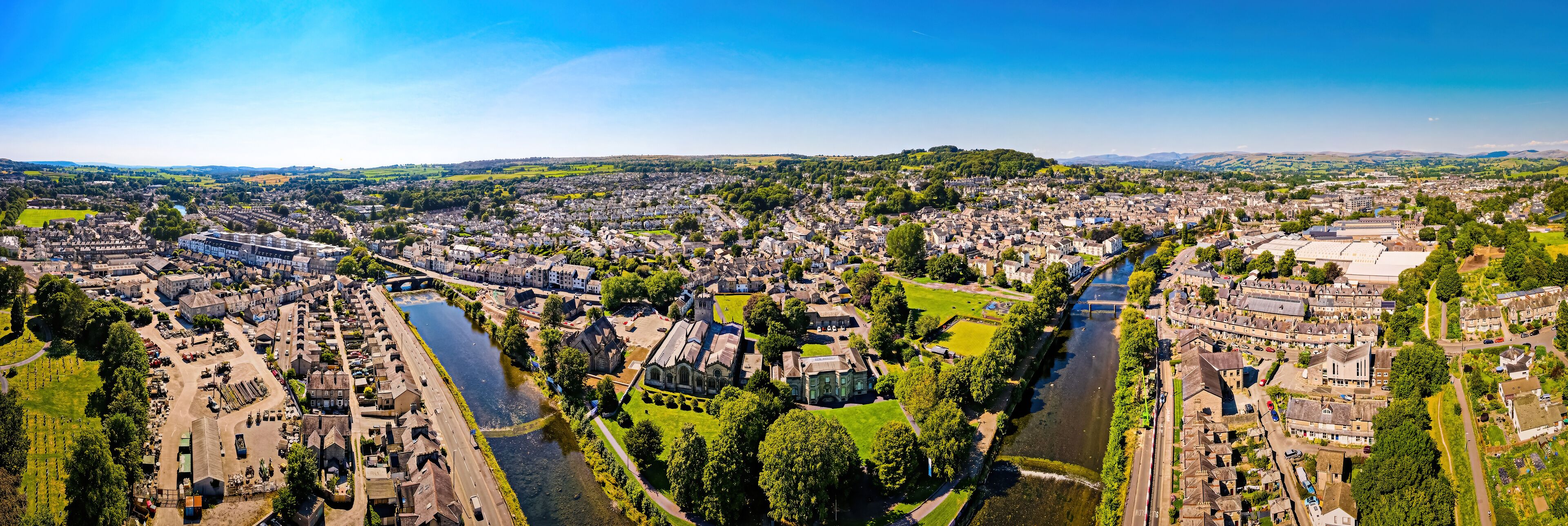 An aerial view of a town with a river, green spaces, and historic buildings.