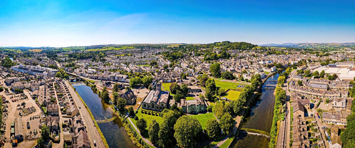 An aerial view of a town with a river, green spaces, and historic buildings.