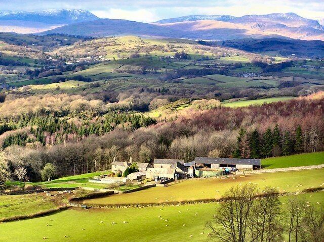 A rural landscape with rolling hills, a farmstead, and a distant mountain range.