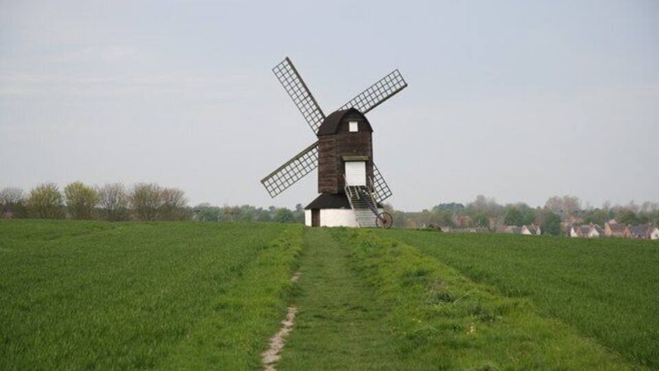 A windmill in a green field with a clear sky.