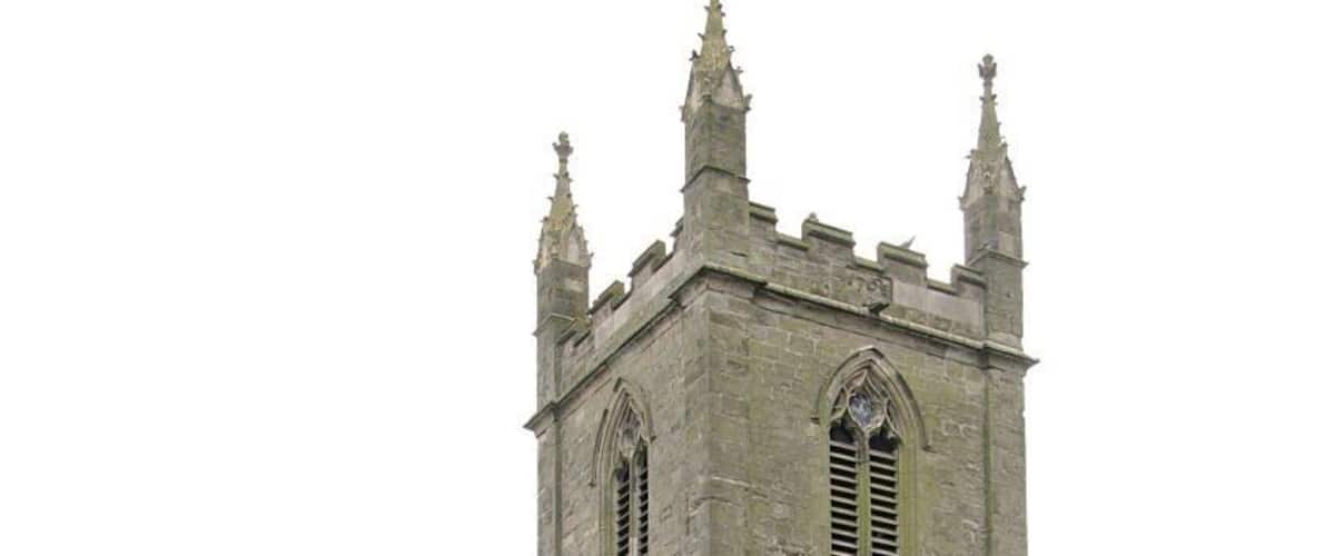 A historic stone church with a tall tower and arched windows.