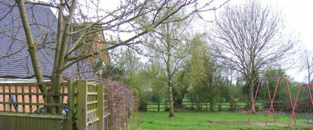 A park with a wooden fence, a bench, and swings.