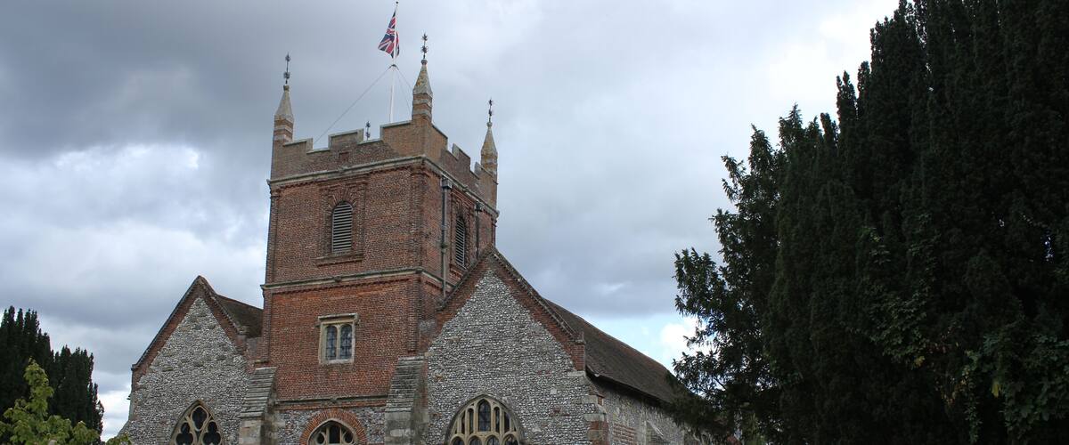 A historic church with a tall tower, stone walls, and a surrounding graveyard.