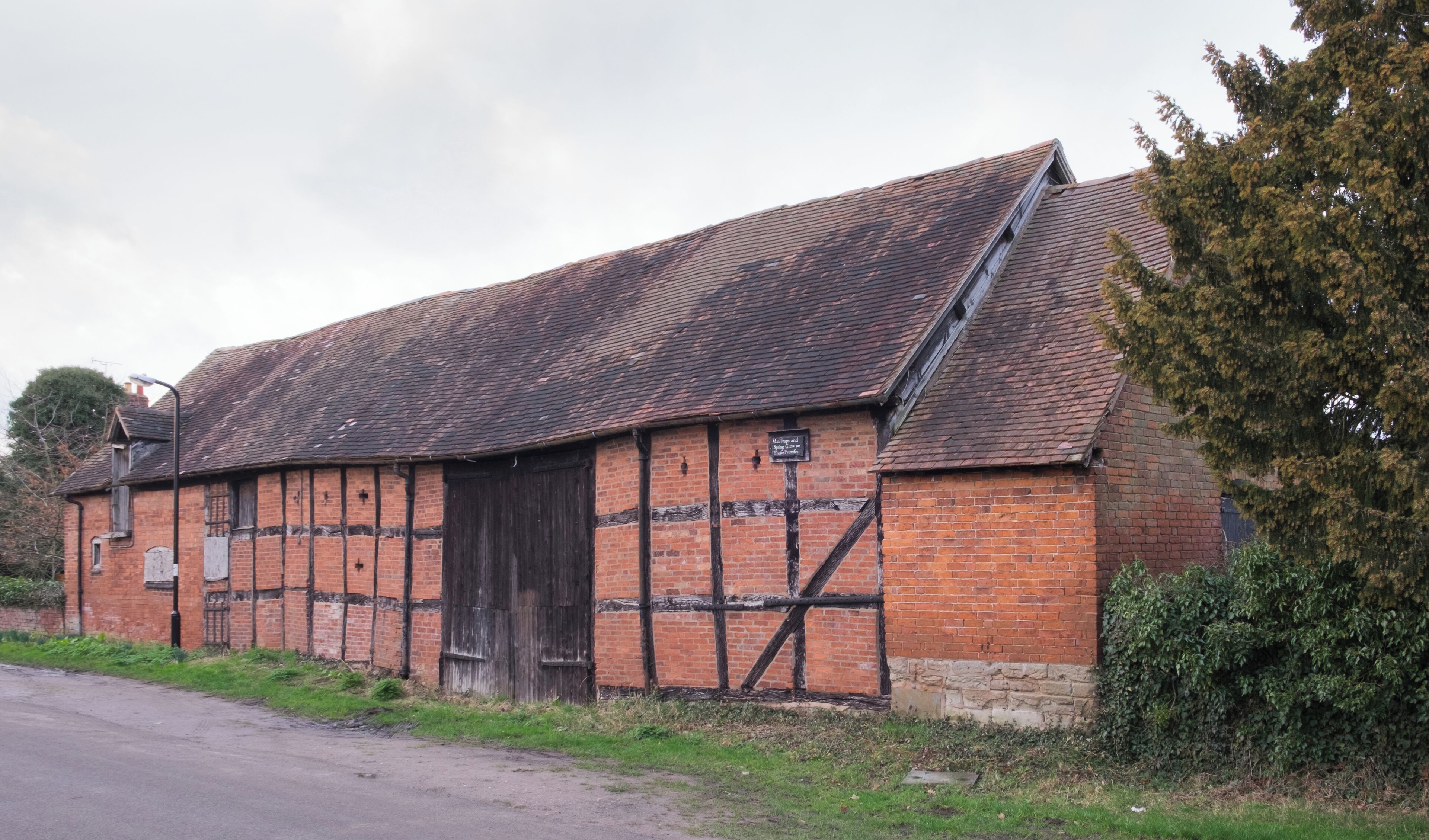 An historic barn in Old Milverton, Warwickshire. The curious sign warns of "Man Traps and Spring Guns on These Premises". This barn, the major part of which was built in the 17th century, is a Grade II Listed Building in England.