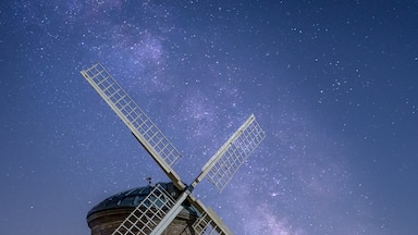 Un moulin à vent historique, avec un ciel étoilé en arrière-plan.