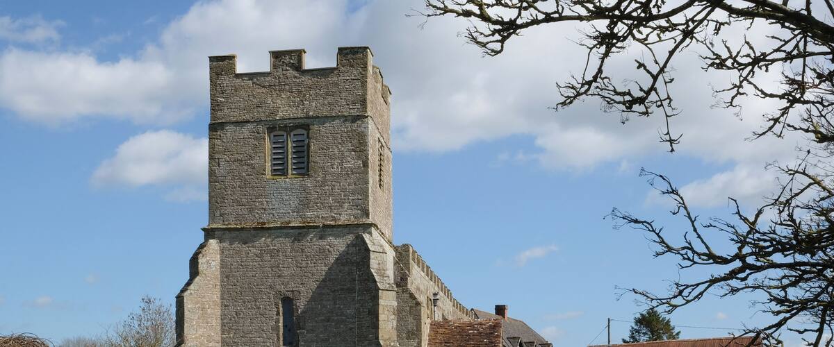 A historic stone church with a tall tower and a graveyard with headstones.