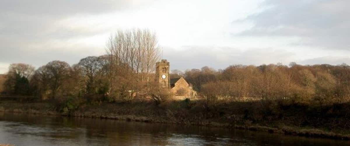 A river with a church and tower on the opposite bank.