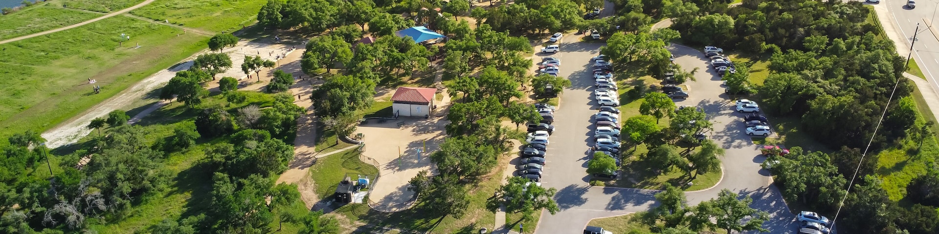 Vista aérea de un estacionamiento rodeado de vegetación y un cuerpo de agua.