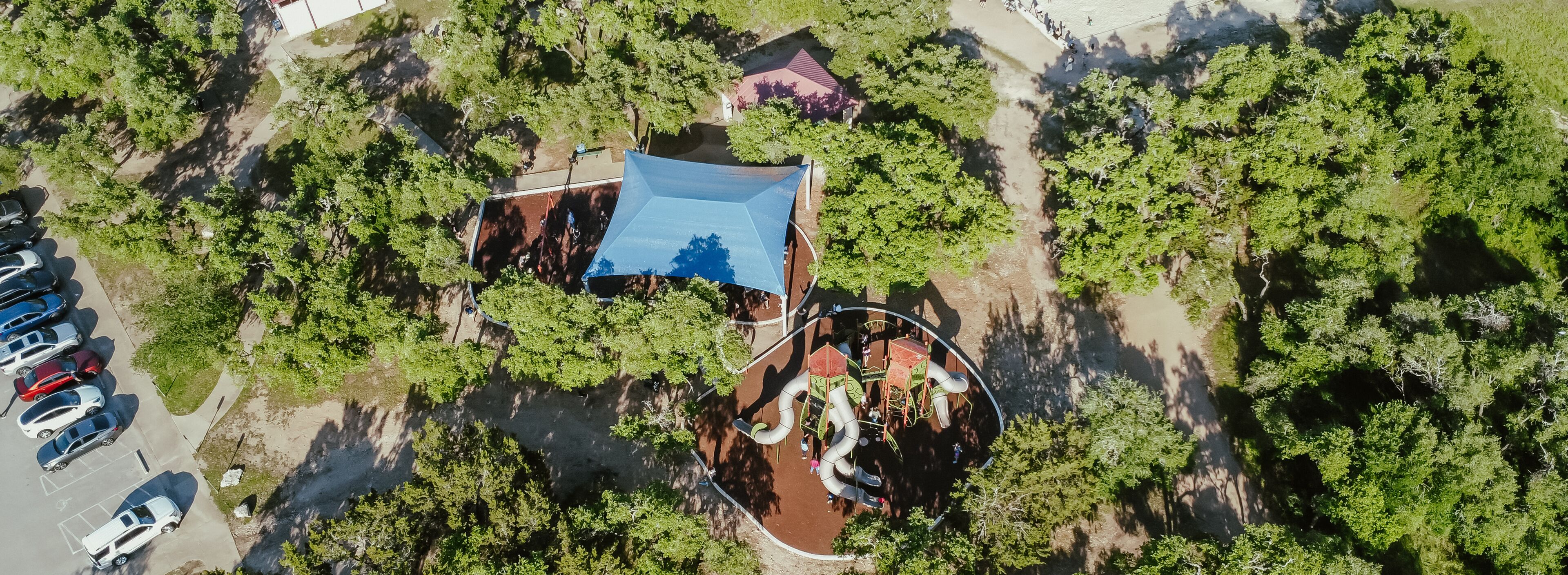 Panorama aerial view busy parking at Brushy Creek Lake Park with modern tower playground sail shade, sand volleyball courts, lush greenery trees, 90-acre park in Cedar Park, suburbs Austin, Texas