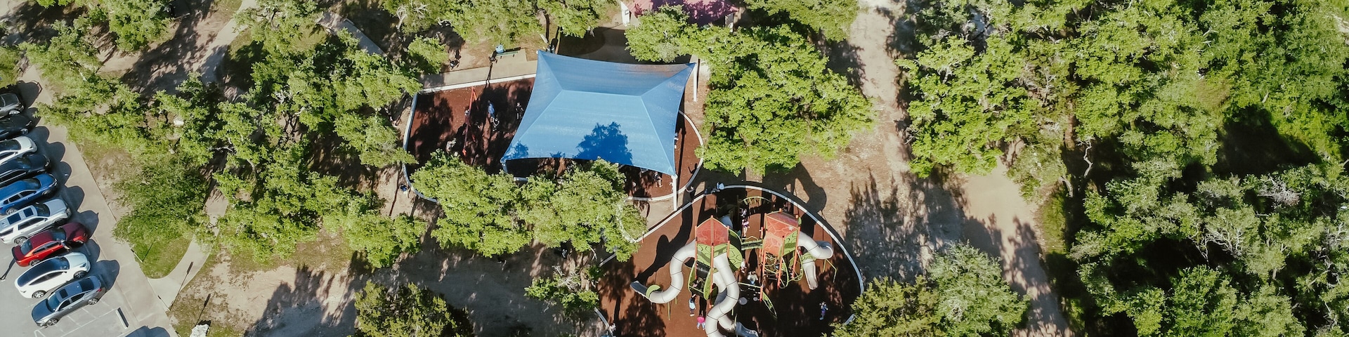 Eine Vogelperspektive eines Parks mit Spielplatz, Parkplatz und umgebender Bepflanzung.