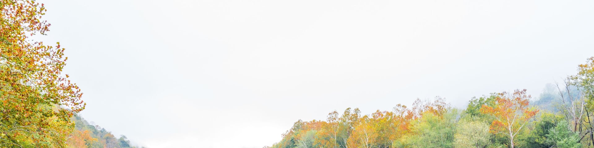 New River Gorge wide canyon water river lake during autumn golden orange foliage in fall by Grandview with peaceful calm tranquil morning bright mist fog