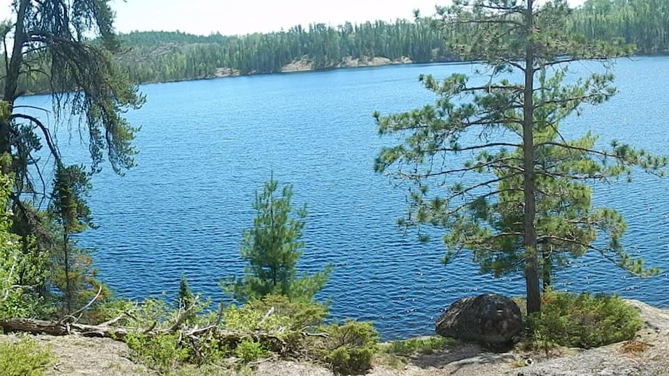 A lake surrounded by dense forest and rocky terrain.