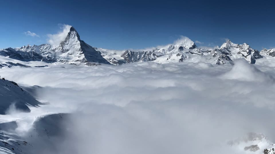 A snow-covered mountain peak with a clear sky above.