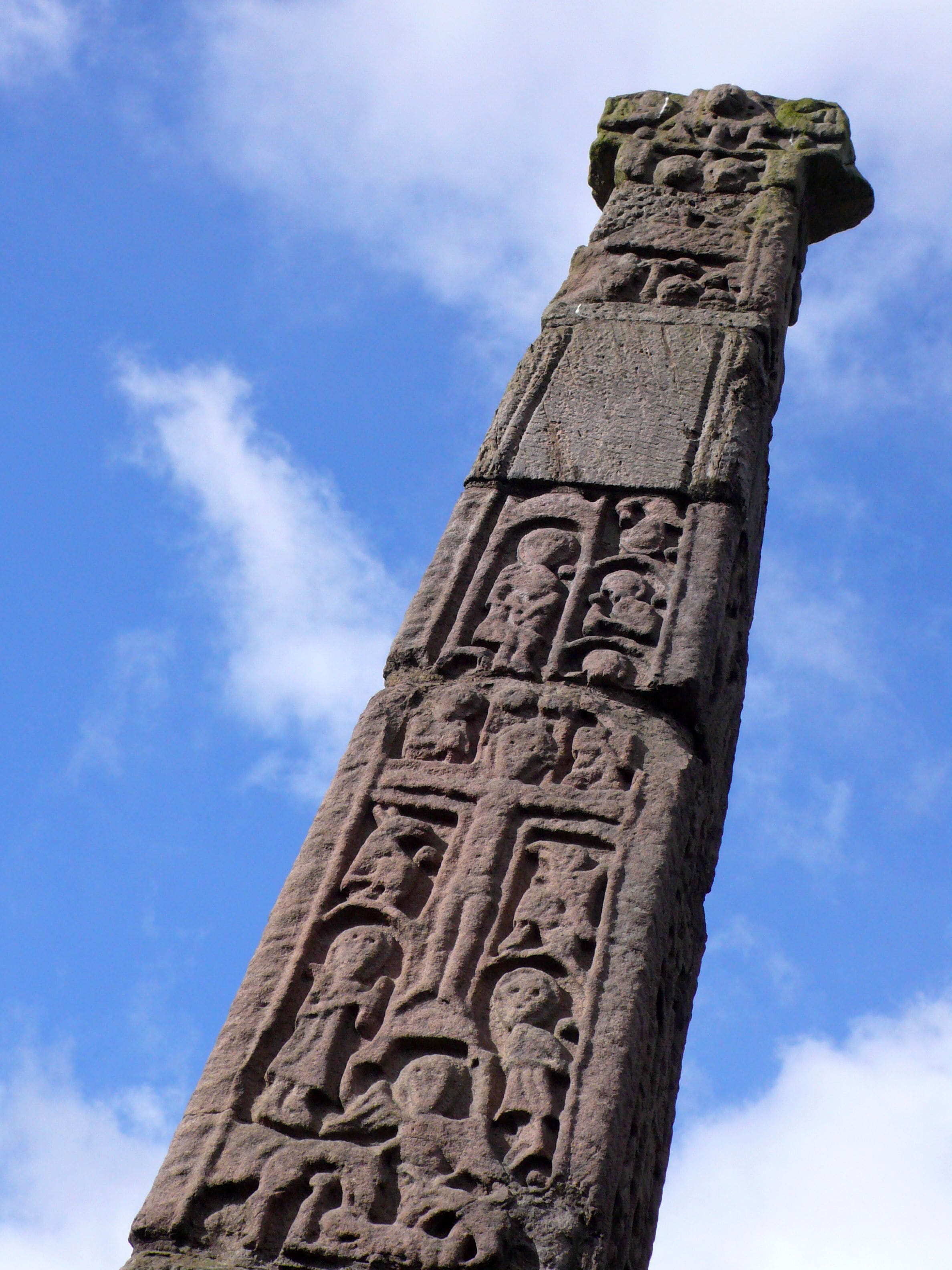 A tall stone monument with intricate carvings against a clear blue sky.