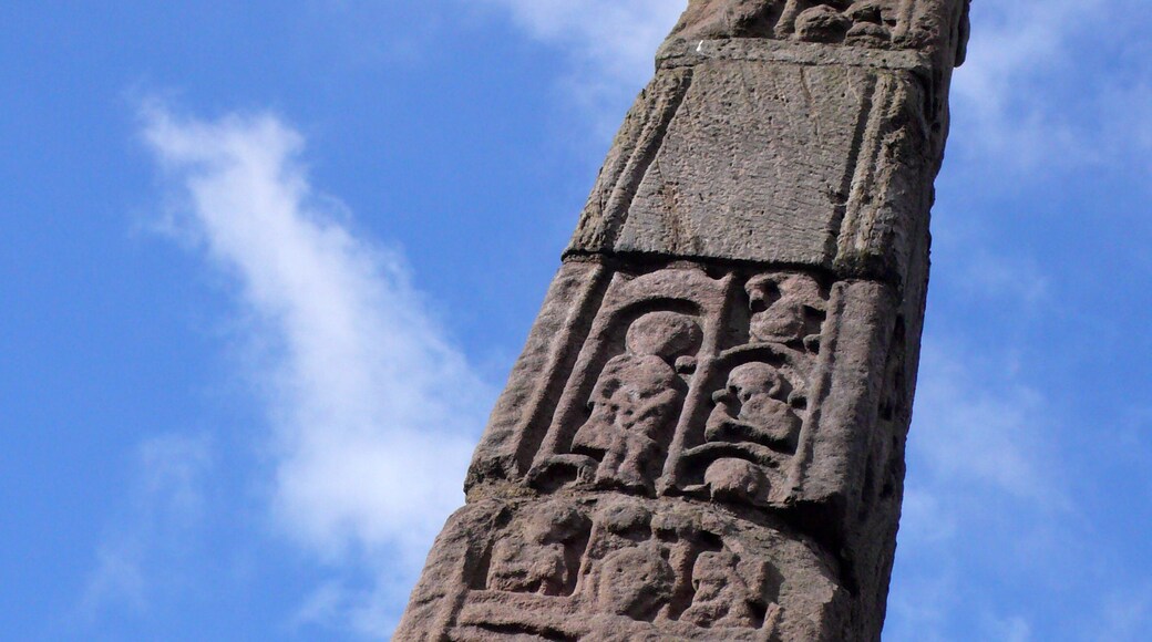 A tall stone monument with intricate carvings against a clear blue sky.