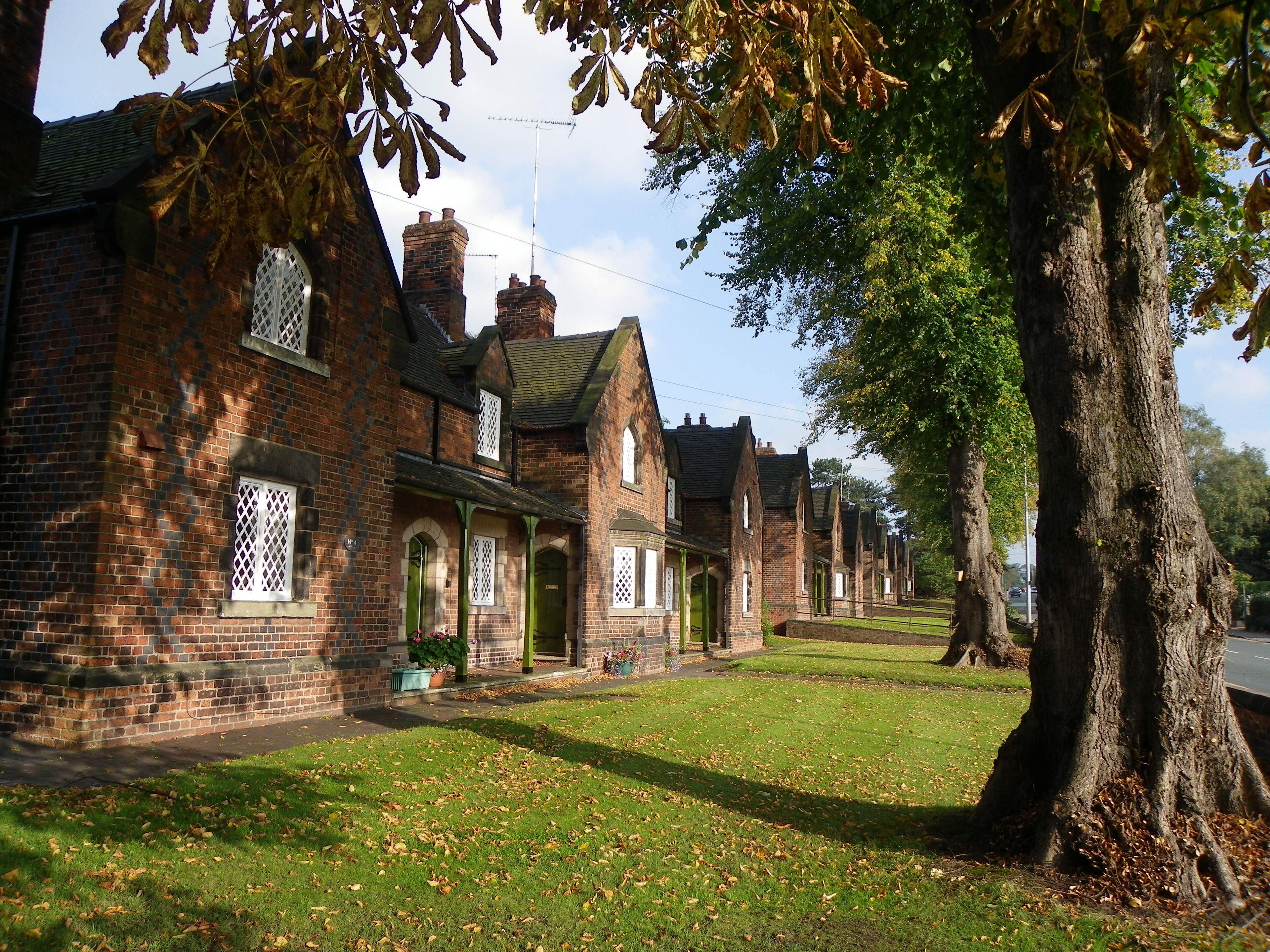 A row of traditional brick houses with green doors and white lattice windows.