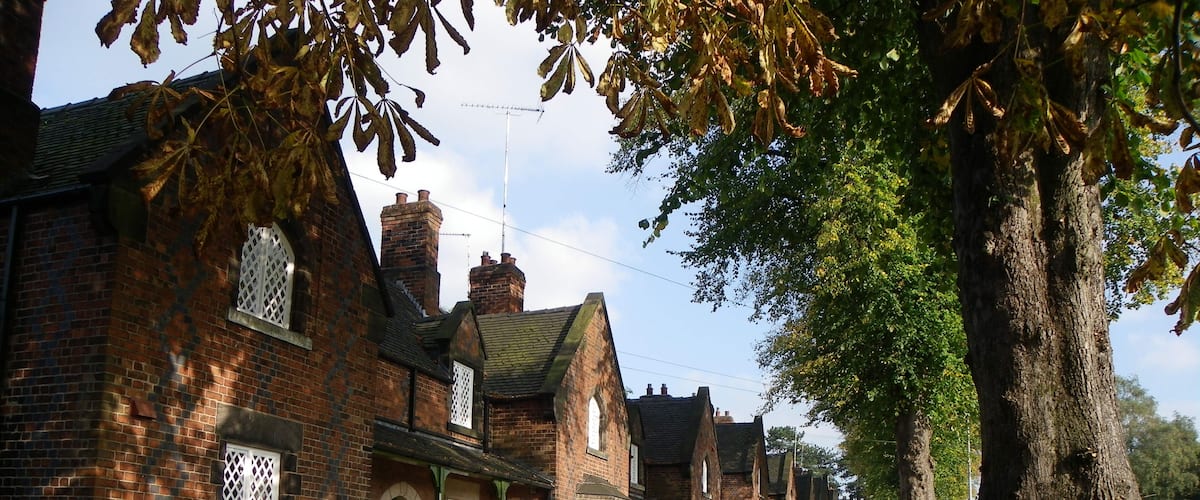 A row of traditional brick houses with green doors and white lattice windows.