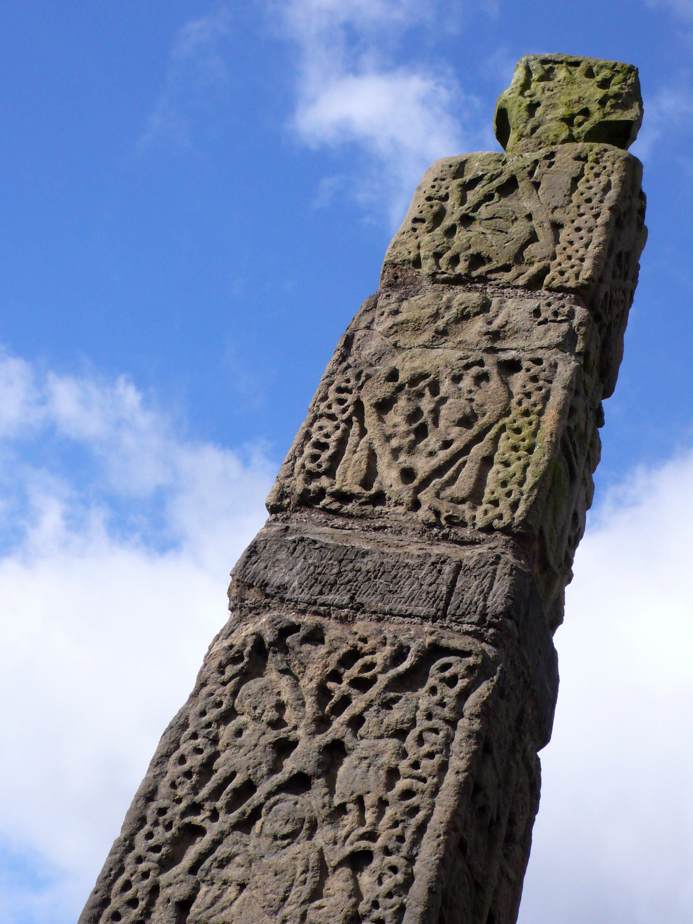 A tall, intricately carved stone monument against a clear blue sky.