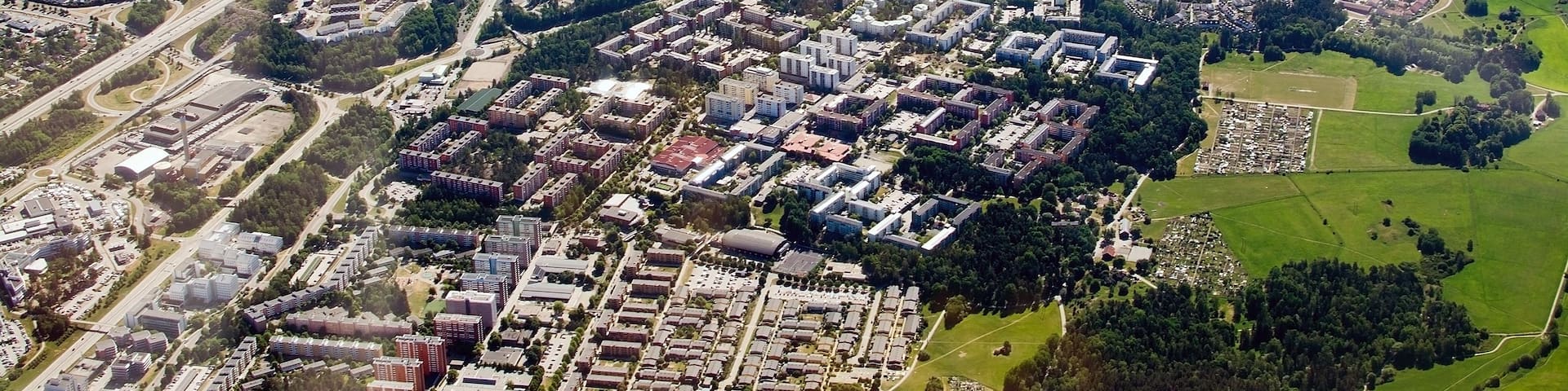 An aerial view of a city with a river, highways, and a mix of residential and commercial buildings.