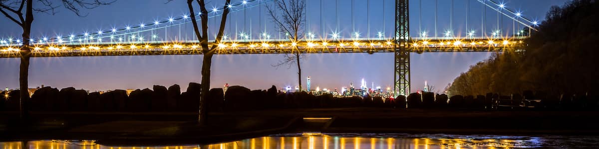 A bridge at night with lights reflecting on water.