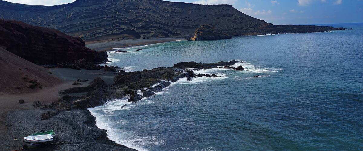 A surreal black sand beach with fishing boats on the west coast of Lanzarote â formed over centuries by the ocean from fragments of lava and other volcanic minerals - this volcanic world looks like it belongs to another planet #LifeAtExpedia #SeasideDiscoveries