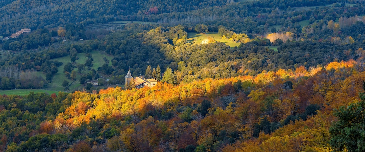 A mountainous landscape with autumn foliage, a church, and rolling hills.