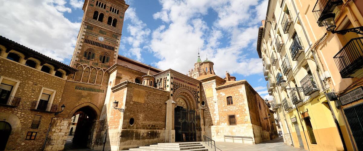 A historic square with a prominent clock tower, a cathedral, and traditional buildings.
