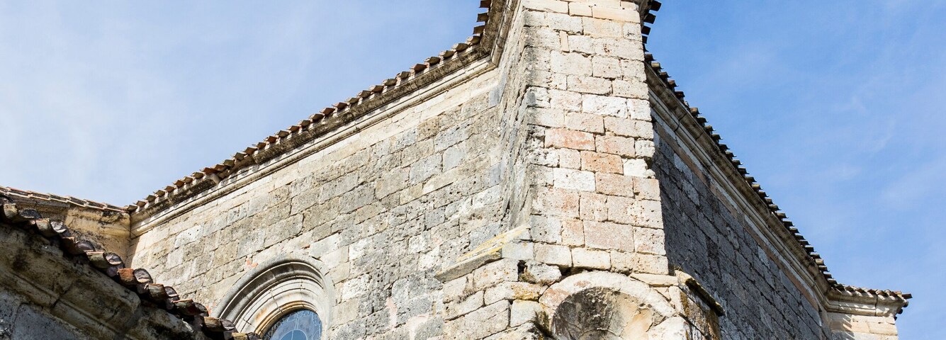 An old stone building with arched windows and a tiled roof.