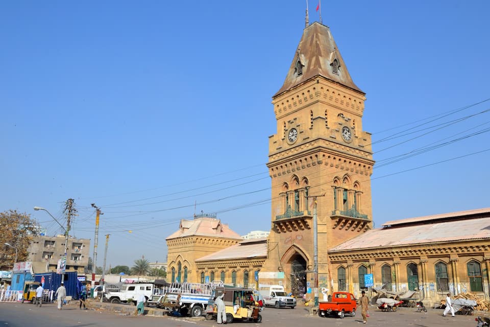 A historic building with a prominent clock tower, a busy street with vehicles, and pedestrians.