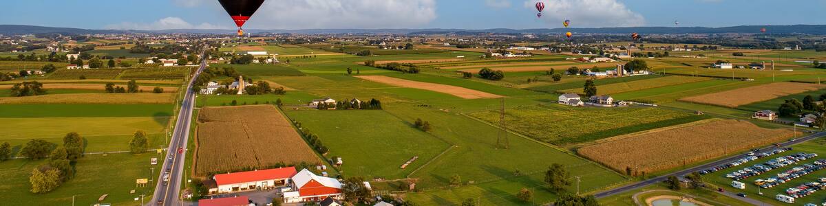 An Aerial View Of Many Hot Air Balloons Launching and Floating Away During a Balloon Festival on a Beautiful Summer Afternoon.