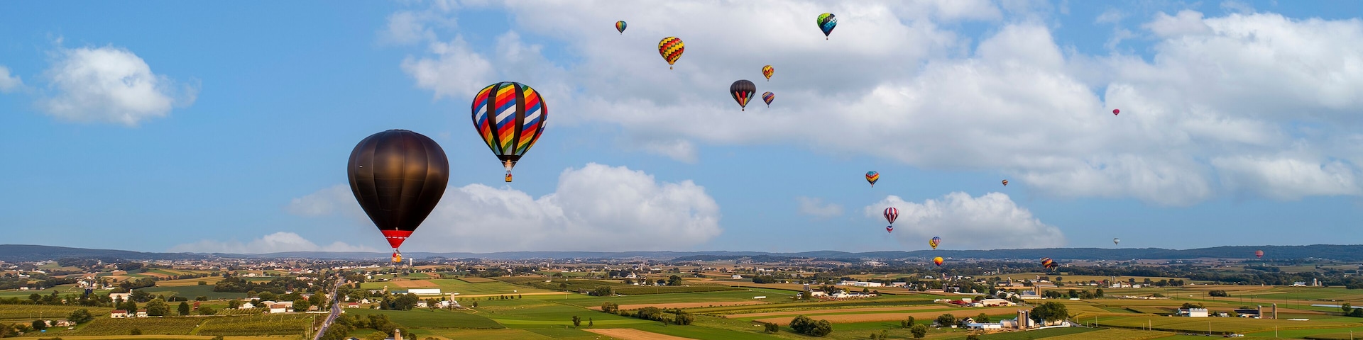 An Aerial View Of Many Hot Air Balloons Launching and Floating Away During a Balloon Festival on a Beautiful Summer Afternoon.