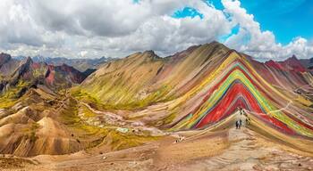 A colorful mountain range with a winding road leading up to a peak.