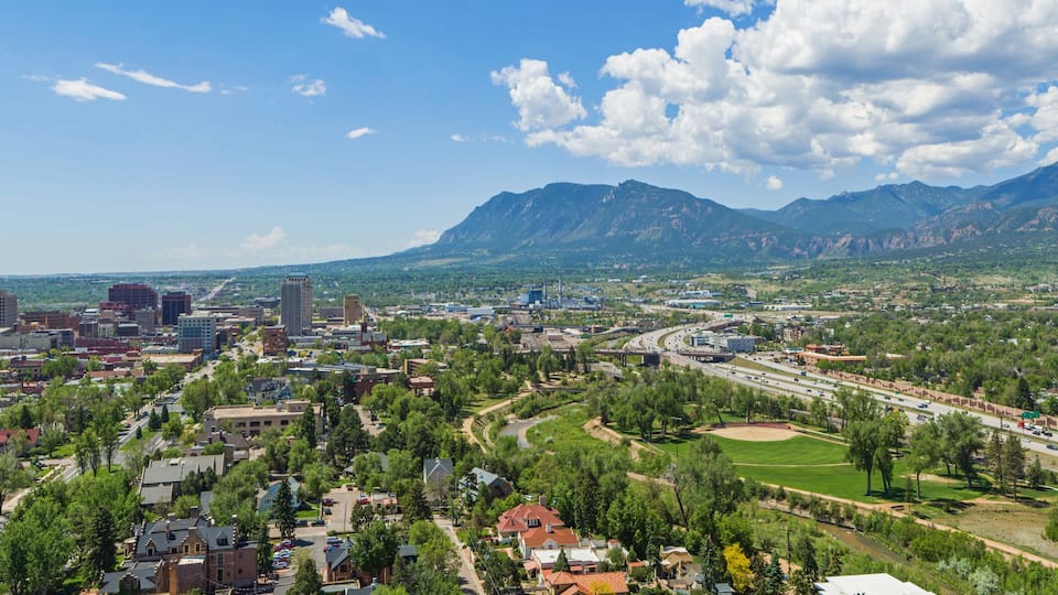 A cityscape with a river, a highway, and mountains in the background.