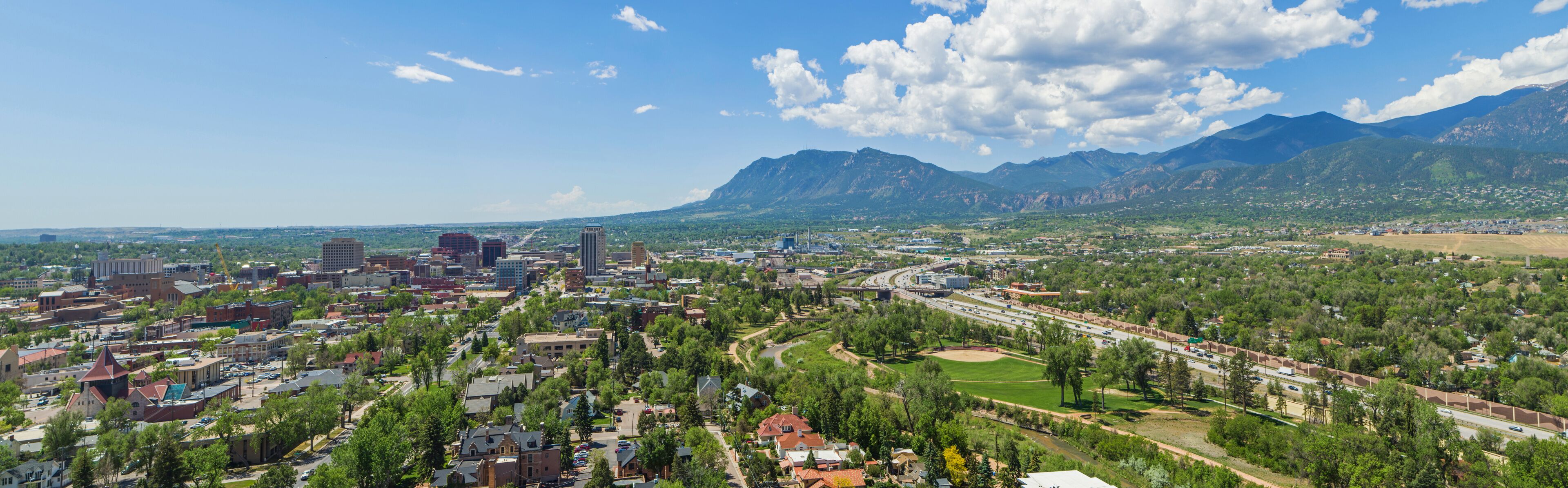 A cityscape with a river, a highway, and mountains in the background.