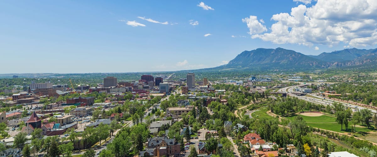 A cityscape with a river, a highway, and mountains in the background.