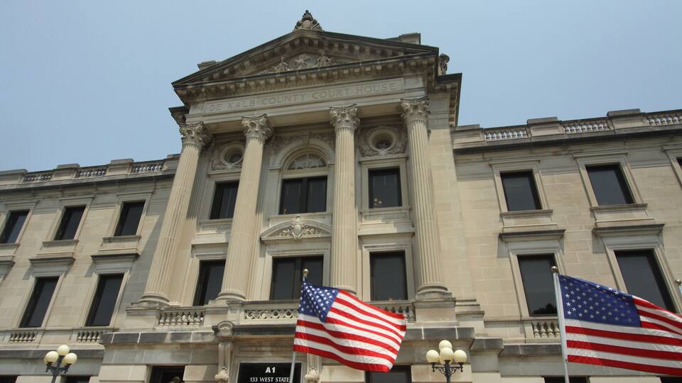 The exterior of the DeKalb County Court House with two American flags in front.