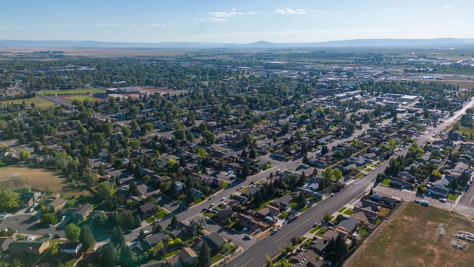 A suburban neighborhood with houses, roads, and distant mountains.