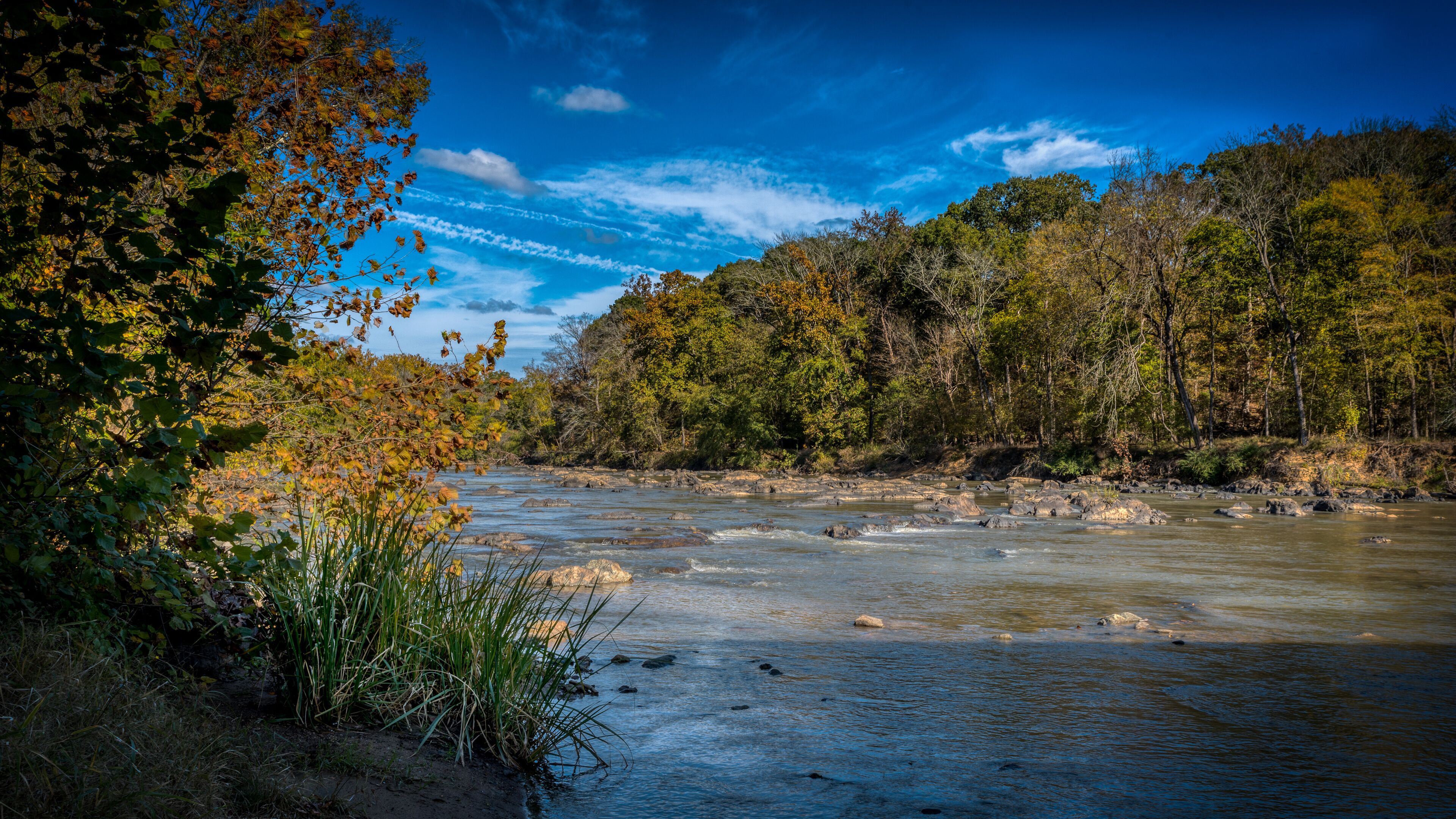 A river flowing through a forested area with autumn foliage.