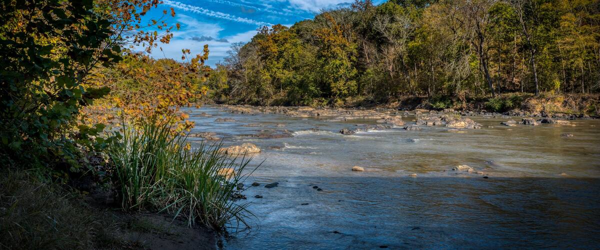 A river flowing through a forested area with autumn foliage.
