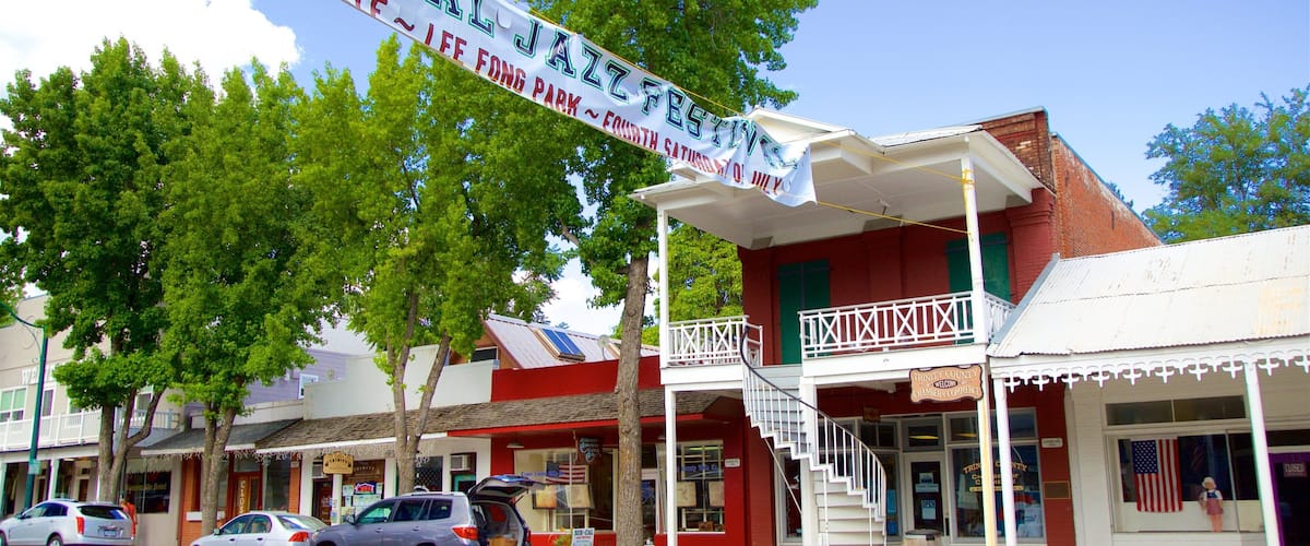 A street with a jazz festival banner, a building with a balcony, and a storefront with an American flag.