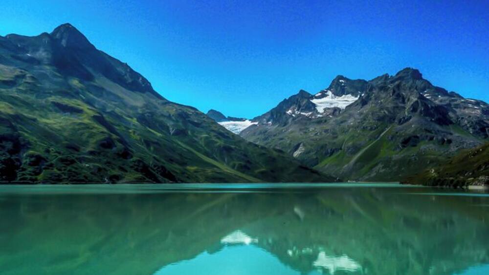 Eine Bergkette mit einem klaren See, der die Berggipfel spiegelt.