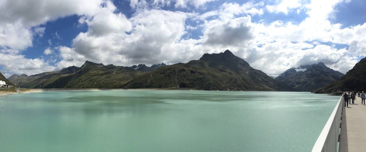 A calm lake surrounded by mountains under a partly cloudy sky.