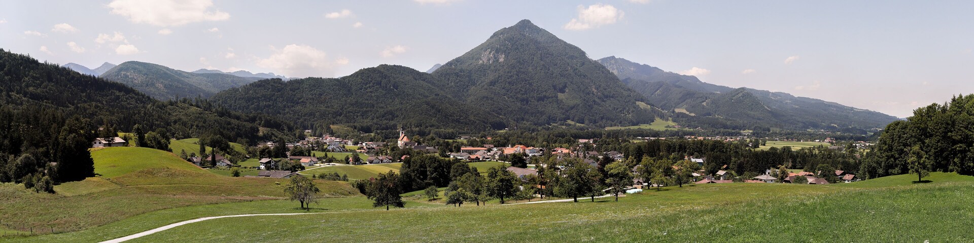 A village nestled in a valley with a prominent mountain in the background.