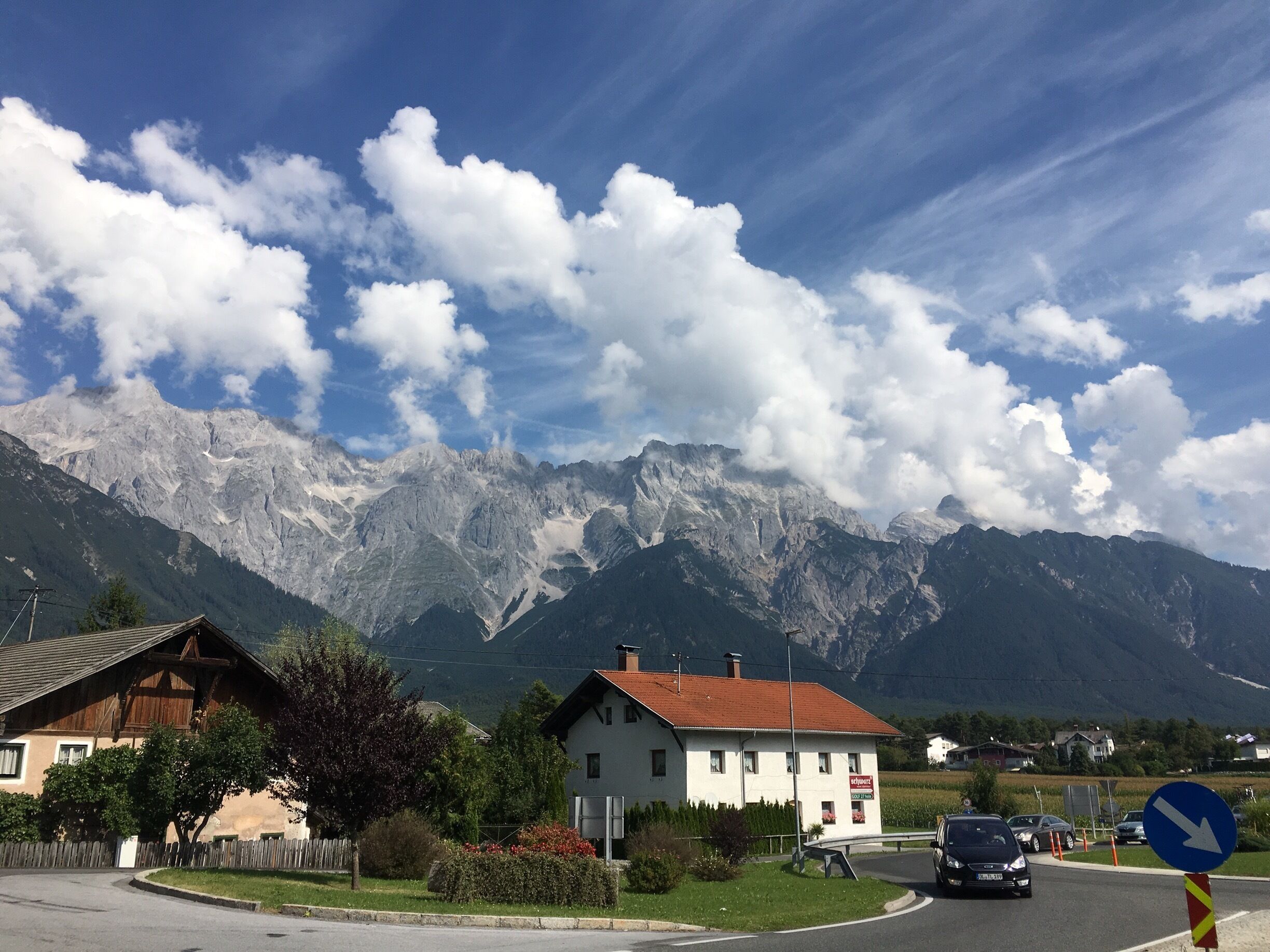 A mountain village with houses, a road, and a mountain range in the background.