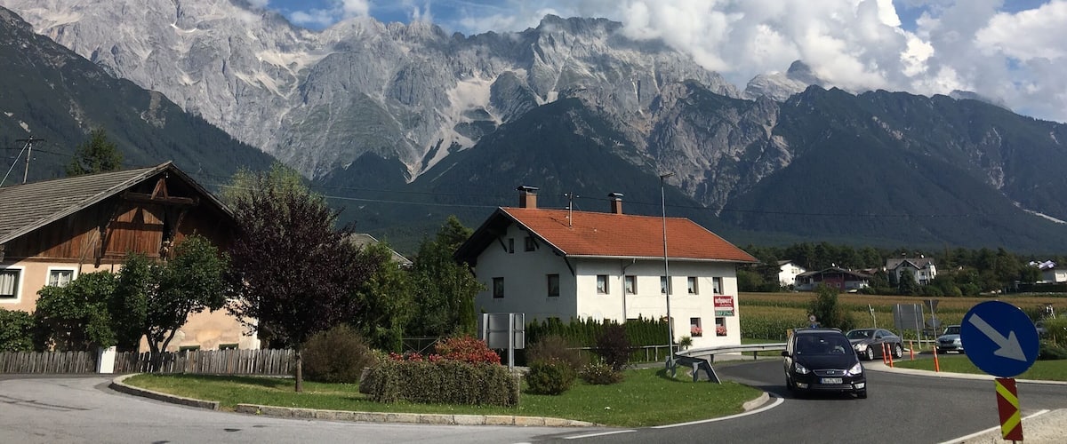 A mountain village with houses, a road, and a mountain range in the background.