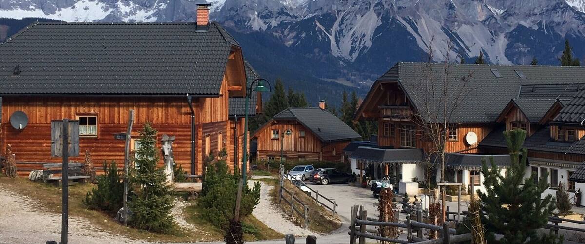 A wooden cabin with a mountain backdrop.
